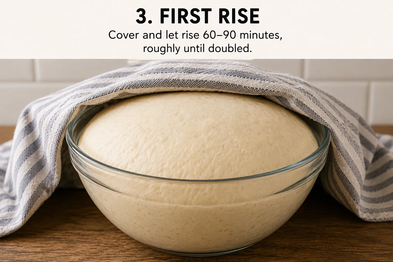 A glass bowl of risen dough domed above the rim, covered with a striped tea towel